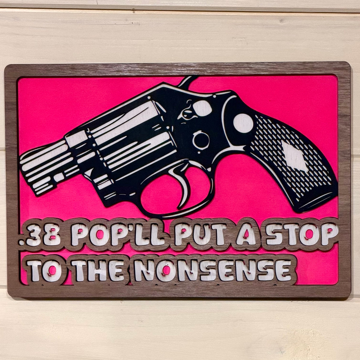 Front view of hot pink layered wooden revolver wall sign