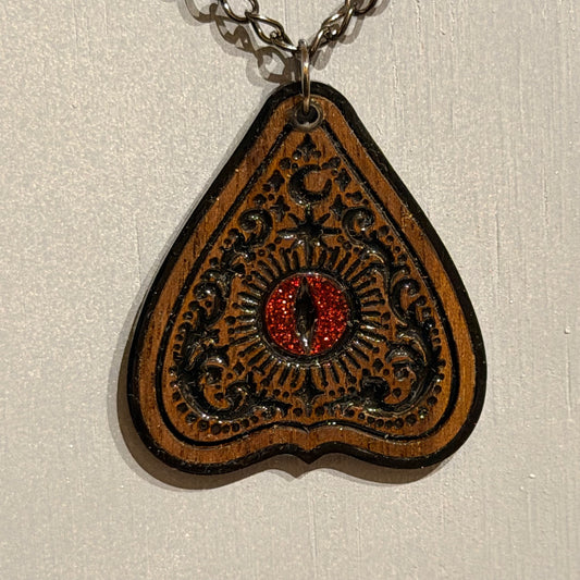 Ouija-inspired wooden planchette pendant with ornate black detail and glossy resin finish