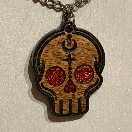 Handmade wooden skull pendant with black engraved details and red glitter acrylic accents