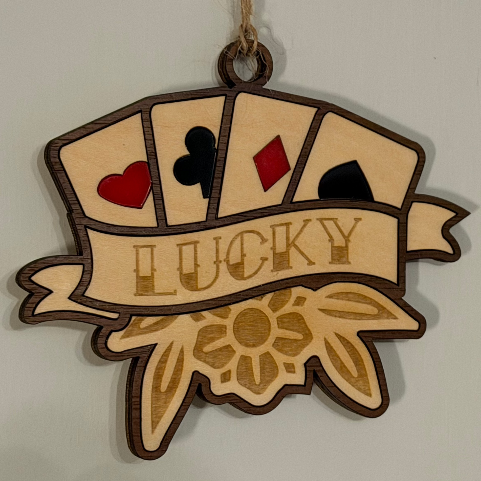 Decorative wooden ornament with playing card symbols and 'LUCKY' text on a plain background