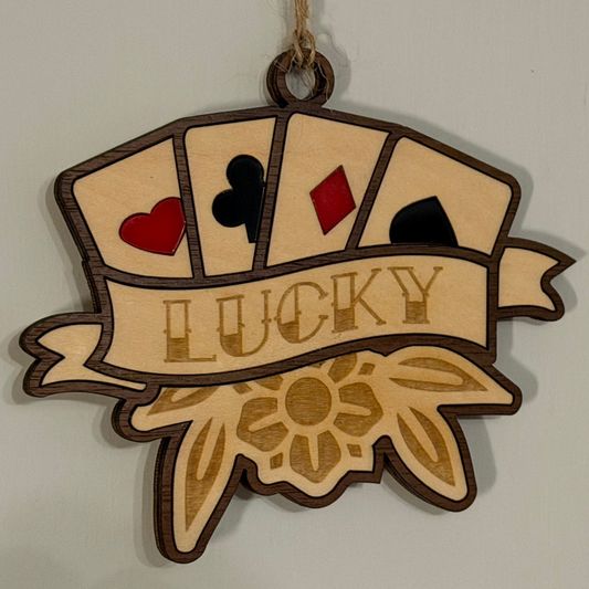 Decorative wooden ornament with playing card symbols and 'LUCKY' text on a plain background