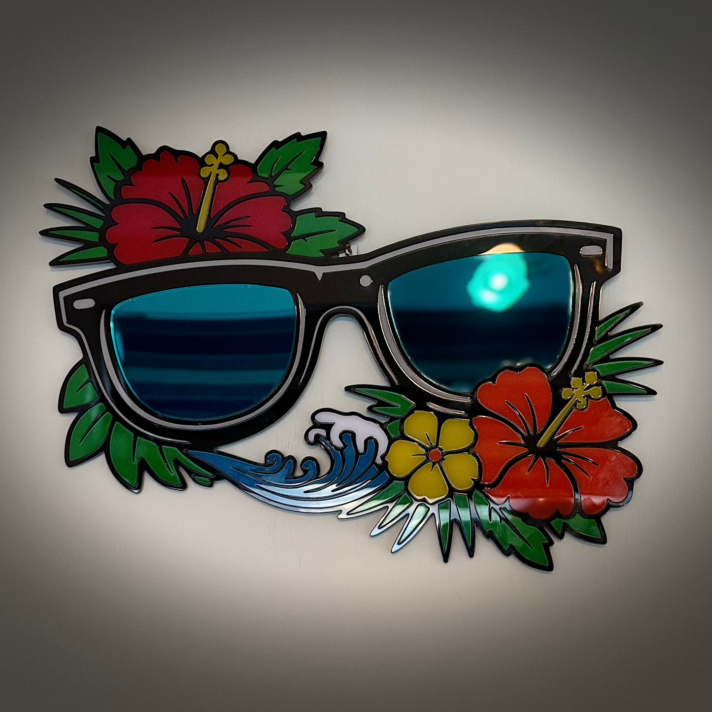 Decorative wall art with sunglasses and floral elements on a gray background