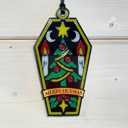 Front view of Merry Hexmas coffin ornament hanging against a white timber background