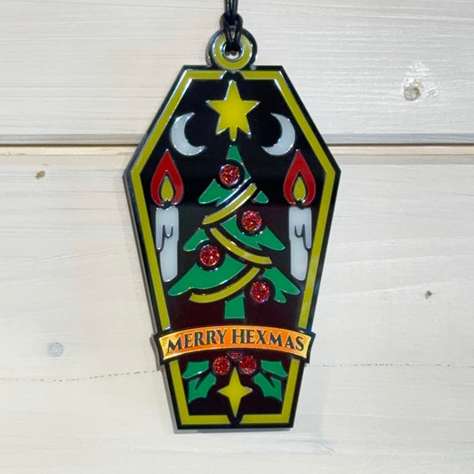 Front view of Merry Hexmas coffin ornament hanging against a white timber background